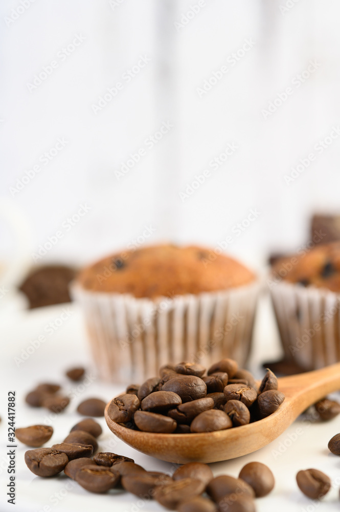 Coffee beans on wooden spoon and Banana Cupcakes on a white wood table.