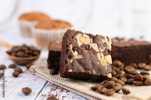 Chocolate brownies on sackcloth and coffee beans on a wooden table.