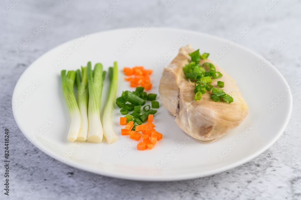 Steamed chicken breast on a white plate with spring onions and chopped carrots Steamed chicken breast on a white plate with spring onions and chopped carrots