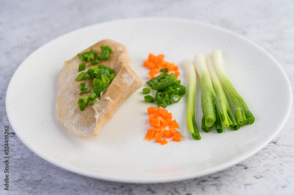 Steamed chicken breast on a white plate with spring onions and chopped carrots Steamed chicken breast on a white plate with spring onions and chopped carrots