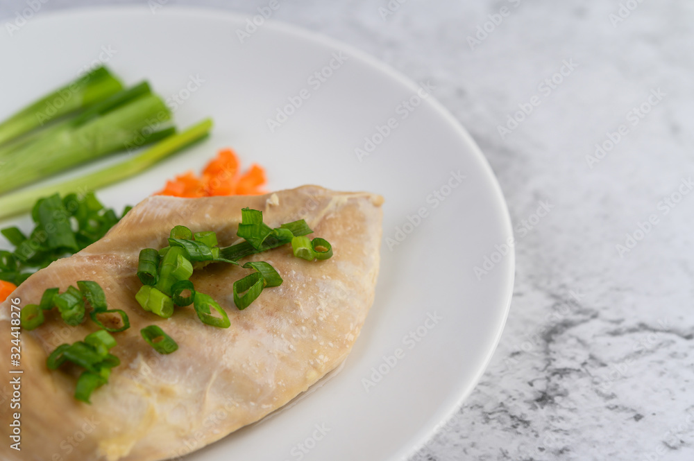Steamed chicken breast on a white plate with spring onions and chopped carrots Steamed chicken breast on a white plate with spring onions and chopped carrots