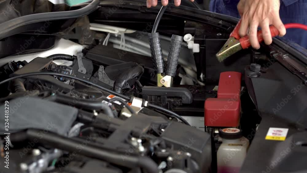 mechanic hand charging battery car with electricity through jumper cables mechanic hand charging battery car with electricity through jumper cables