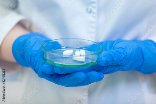 Technician holding Petri dish with pills. Scientists create new drugs and vaccines in a modern scientific laboratory