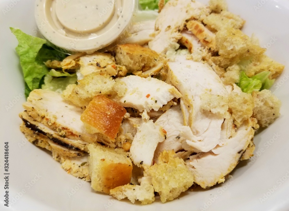 Grilled chicken caesar salad inside a white bowl Grilled chicken caesar salad inside a white bowl