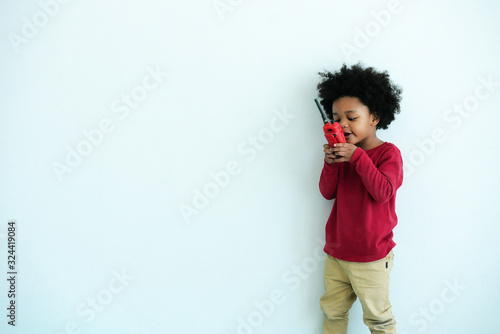 African-American little boy happy to play talking with toy walkie talkie radio on white background.