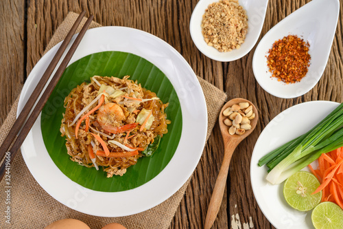 Padthai shrimp in a black bowl with eggs, Spring onion, and Seasoning on wooden table. photo