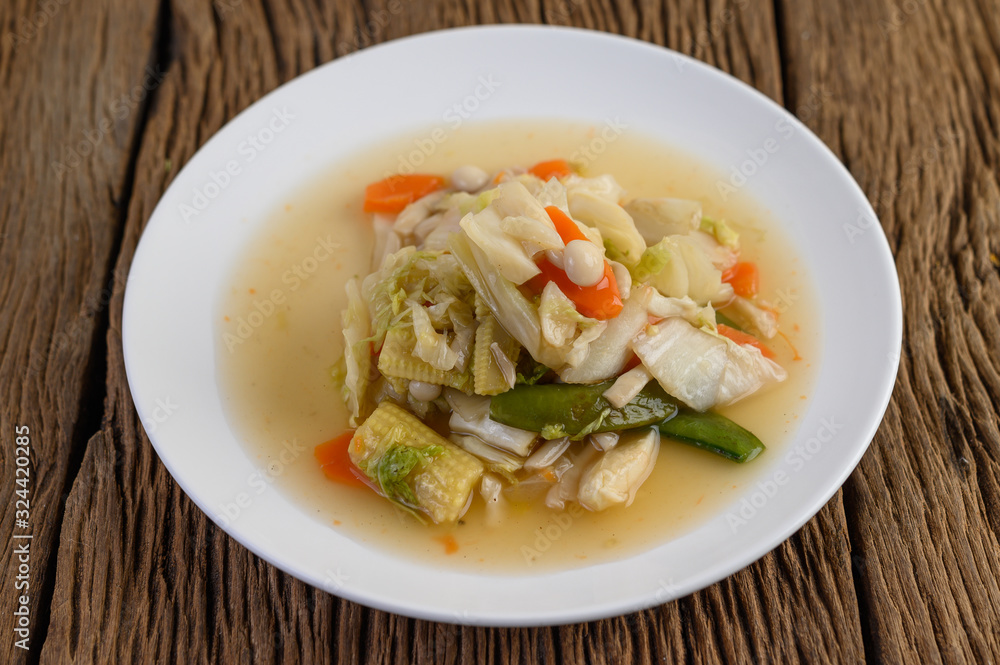 Stir fry mixed vegetables on a white plate on a wooden table. Stir fry mixed vegetables on a white plate on a wooden table.