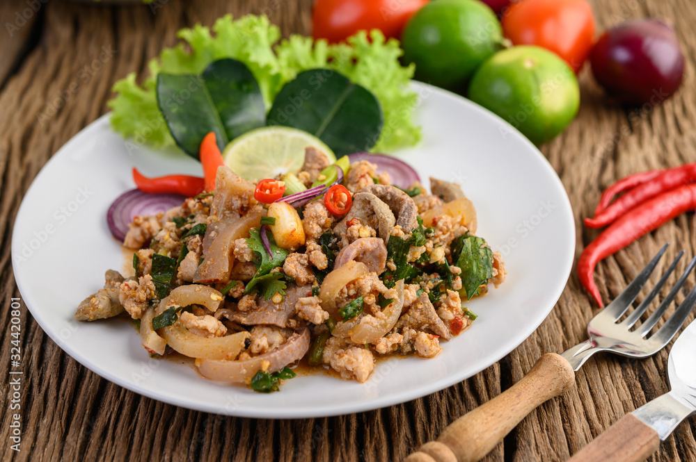Spicy Minced Pork Salad on a white plate on wooden table. Spicy Minced Pork Salad on a white plate on wooden table.