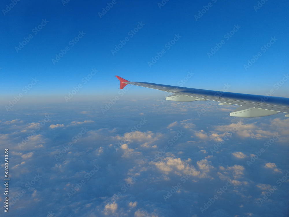 Obraz premium flying in a plane in the sky above the clouds on the wing at dawn aviation vacation