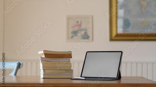 Close up view of workplace with mock up digital tablet and books on wooden desk © bongkarn