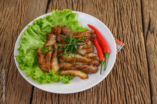 Grilled pork neck on a white plate on a wooden table