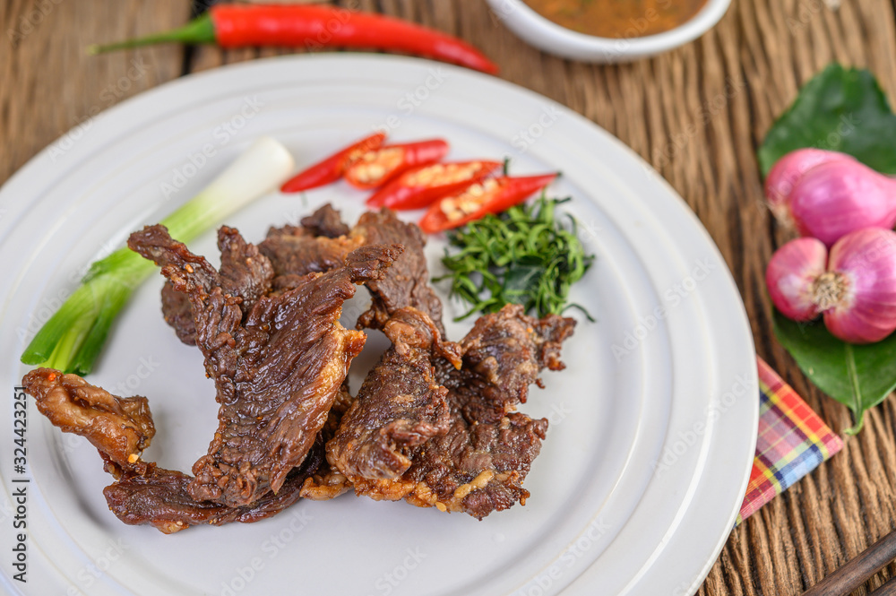 Beef fried Thai food on a white plate with spring onion, kaffir lime leaves, chilies, red onions and tomatoes. Selective focus. Beef fried Thai food on a white plate with spring onion, kaffir lime leaves, chilies, red onions and tomatoes. Selective focus.