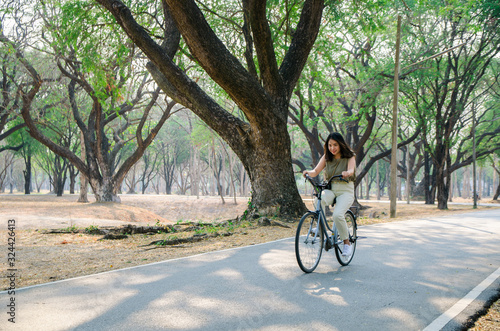 asian girl is riding bicycle on road in park with smile face