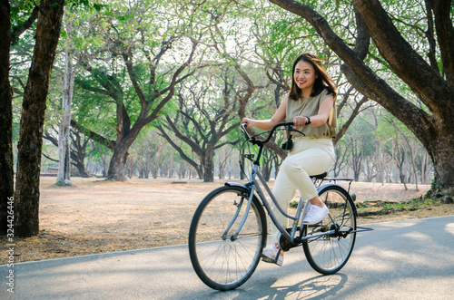asian girl is riding bicycle on road in park with smile face