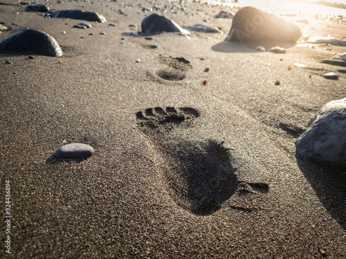 Beautiful image of footprint on wet ocean beach sand between rocks at sunset