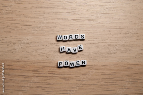 Word WORDS HAVE POWER in white cubes on light wooden background for your design templates