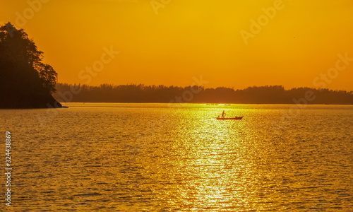 Sea view morning of a fishing boat rowing in the sea with yellow sun light in the sky background, sunrise at Mu Ko Phetra National Park, pak nam, la-ngu district, Satun, Thailand.