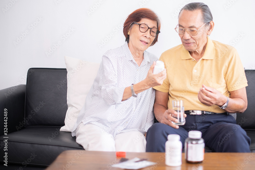 Asian retired man taking medicine at home.Senior Asian couple take pill medicine or vitamin pills for health care Asian retired man taking medicine at home.Senior Asian couple take pill medicine or vitamin pills for health care