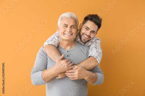 Young man and his father on color background photo