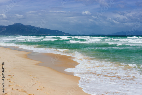 Empty long beach with a beautiful sea view. White foam from a sea wave