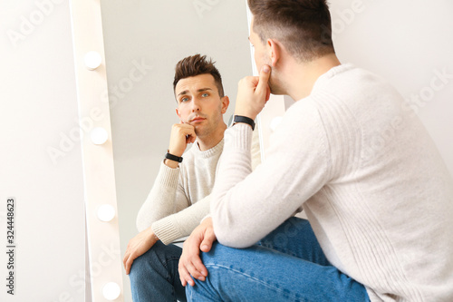 Thoughtful young man looking at his reflection in mirror © Pixel-Shot