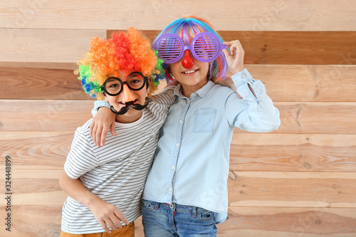 Little children in funny disguise on wooden background. April fools' day celebration photo