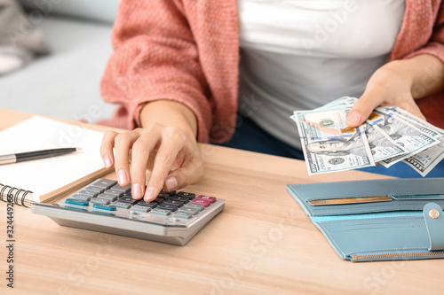Young woman counting money at home, closeup