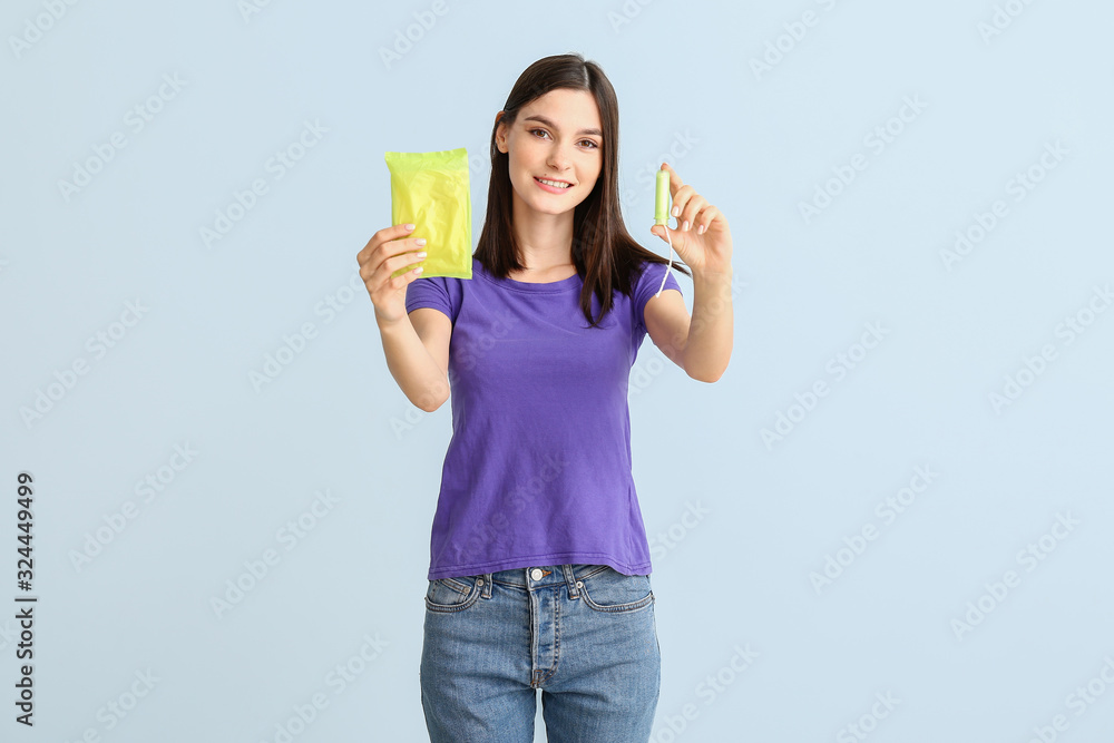 Young woman with pad and menstrual tampon on light background Young woman with pad and menstrual tampon on light background
