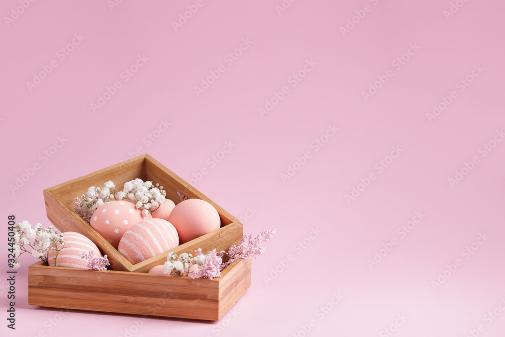 Boxes with beautiful Easter eggs and flowers on color background Boxes with beautiful Easter eggs and flowers on color background