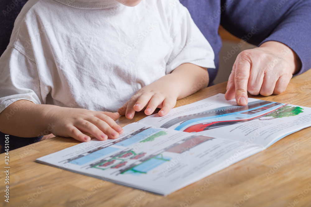 hands mature woman (80 years old) with her great-grandson at home, reading educational book together hands mature woman (80 years old) with her great-grandson at home, reading educational book together