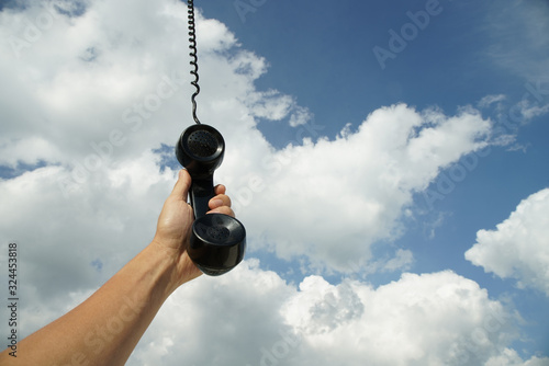 vintage black phone with line hanging from the sky. Conceptual photography talking to someone from above