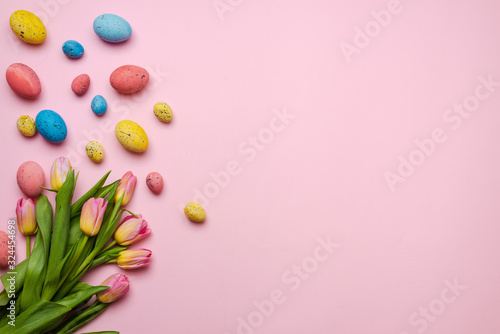 Fototapeta Naklejka Na Ścianę i Meble -  Easter background with colorful eggs and yellow tulips over wood. Top view with copy space