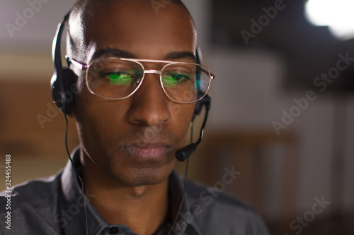 Focused African American man with headset looking down. Front view of call center operator. Call center concept