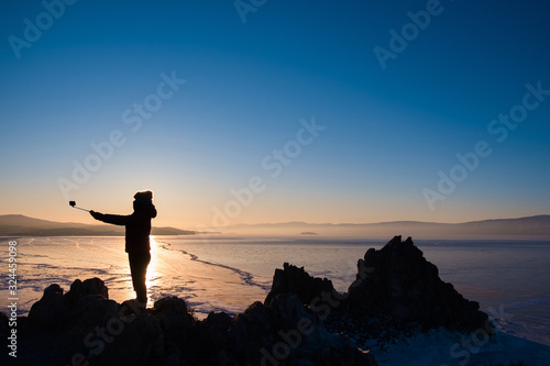 Silhouette of tourist taking selfy during sunset on top of the hill