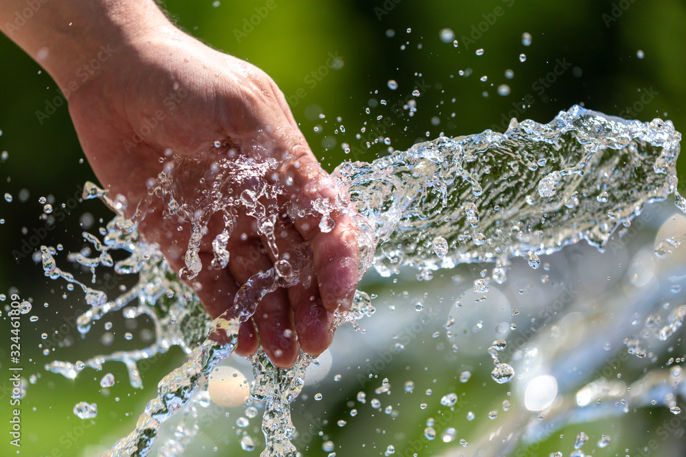 Fototapeta premium Hand of a man in the spray of water of the fountain
