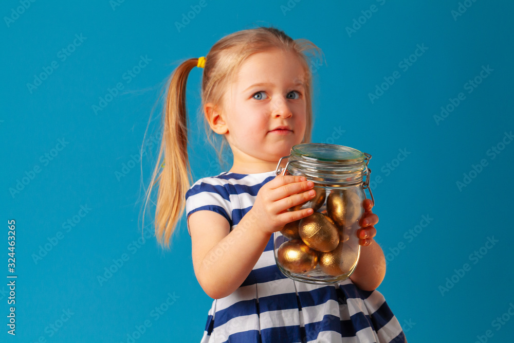 Little cute girl holding glass jar with golden eggs colored for Easter Little cute girl holding glass jar with golden eggs colored for Easter