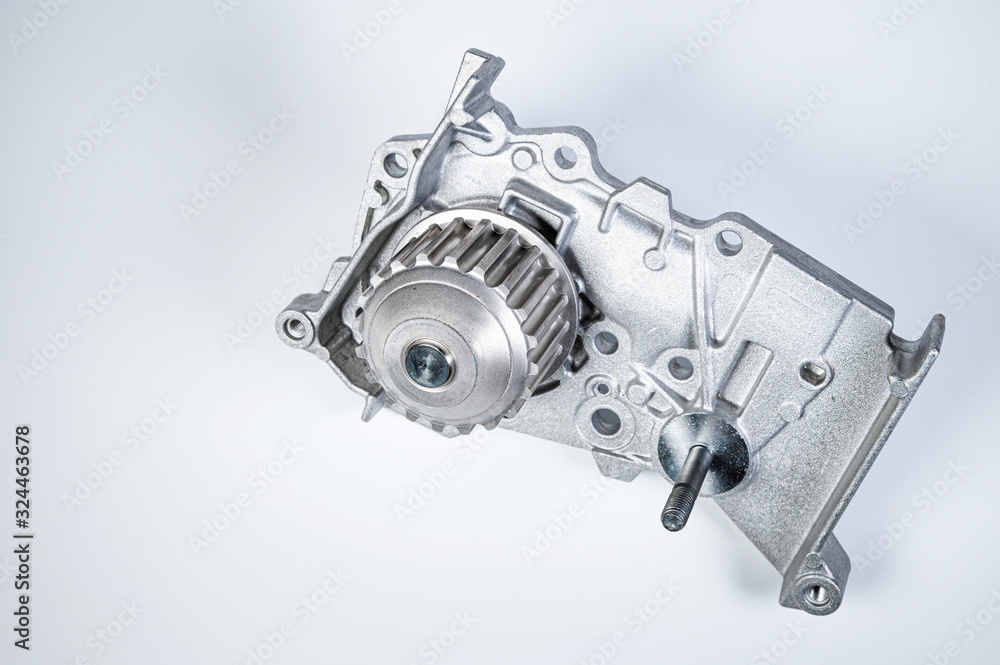 New metal automobile pump for cooling the engine of a water pump on a gray background. The concept of new spare parts for the car engine New metal automobile pump for cooling the engine of a water pump on a gray background. The concept of new spare parts for the car engine
