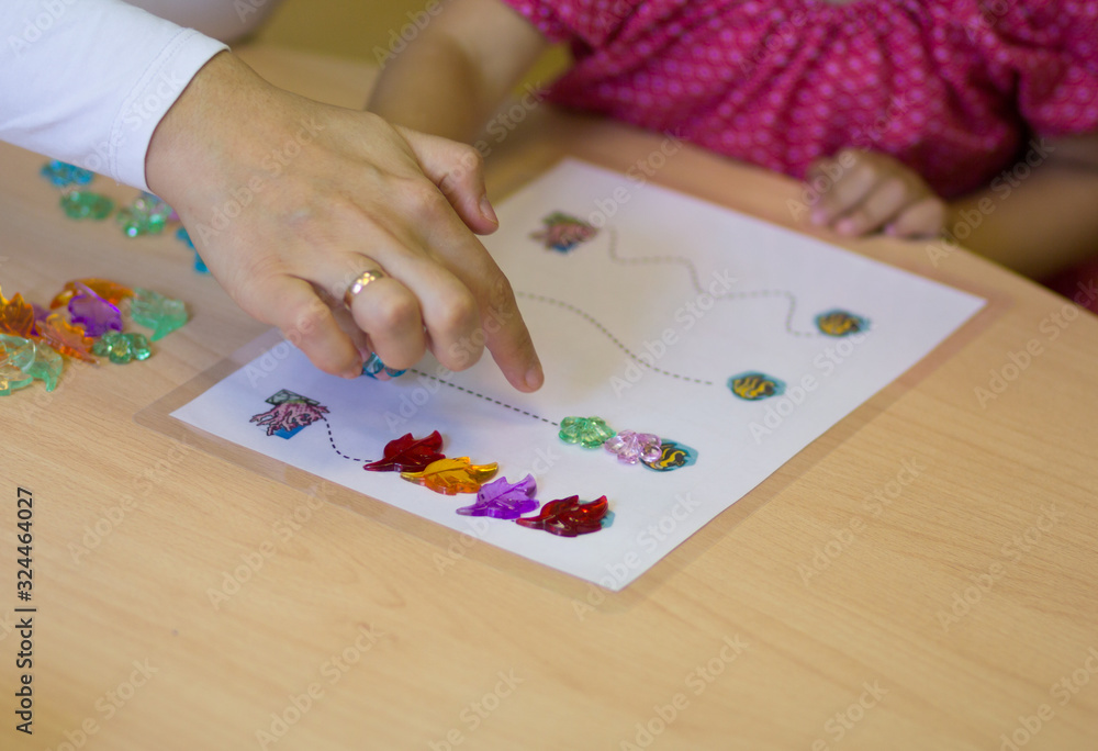 Child hands playing with the colorful stones to develop fine motor skills Child hands playing with the colorful stones to develop fine motor skills