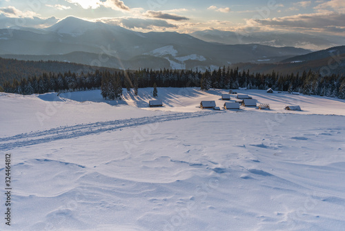 Charming snow-capped houses on a mountain Carpathian mountain valley, with magnificent views of peaks in winter. © reme80