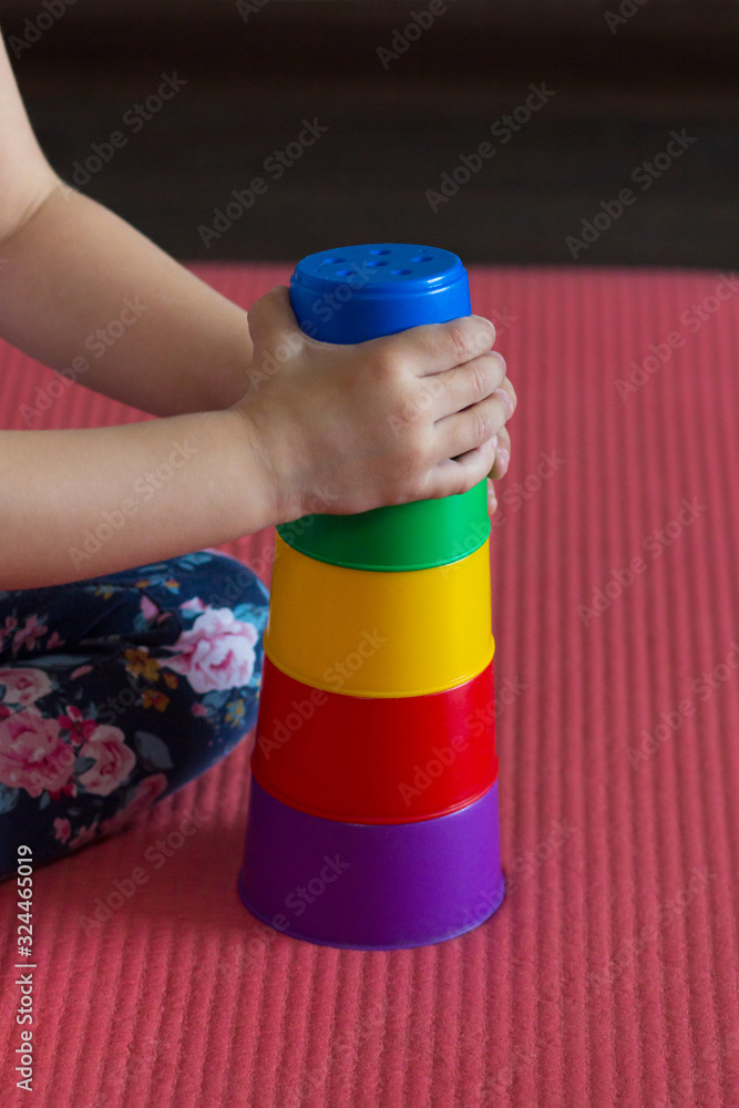 children hands make Pyramid using colorful stacking cups