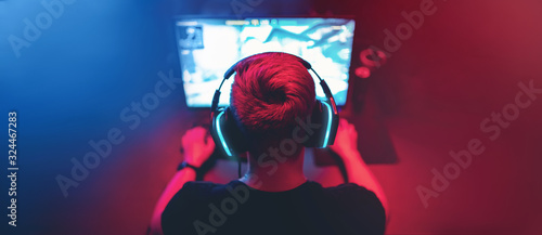 Blurred background professional gamer playing tournaments online games computer with headphones, red and blue photo