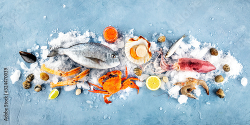Fish and seafood panorama, a flat lay. Sea bream, scallop, crab, squid, clams, shot from the top on ice