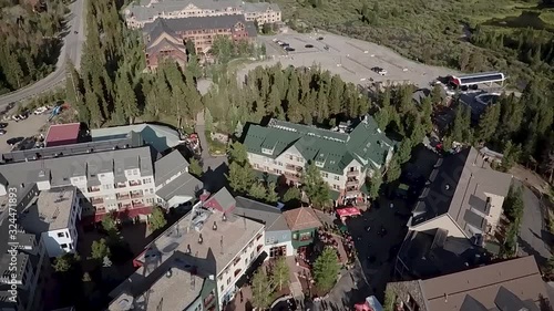 Drone shot looks down on a small village in Colorado and tilts up to reveal the surrounding mountains and blue sky. photo