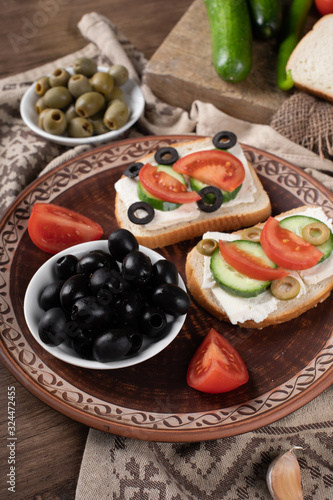 Black olives in a white bowl with sandwiches