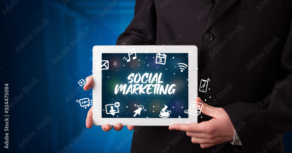 Young business person working on tablet and shows the inscription: SOCIAL MARKETING Young business person working on tablet and shows the inscription: SOCIAL MARKETING