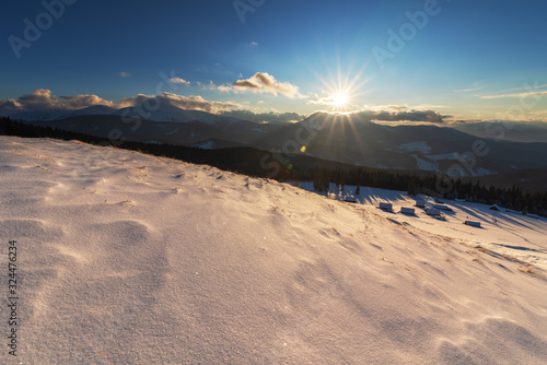 Charming snow-capped houses on a mountain Carpathian mountain valley, with magnificent views of peaks in winter.