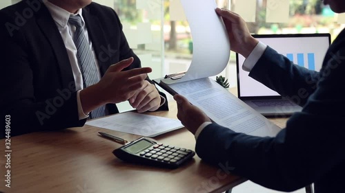 Job interviewers are reading the resume or work history of an employee who applied for a job while the employee is explaining more about his work experience.