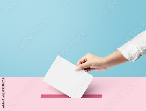 Hand holding ballot paper for election vote concept at blue backdrop. minimal composition concept.