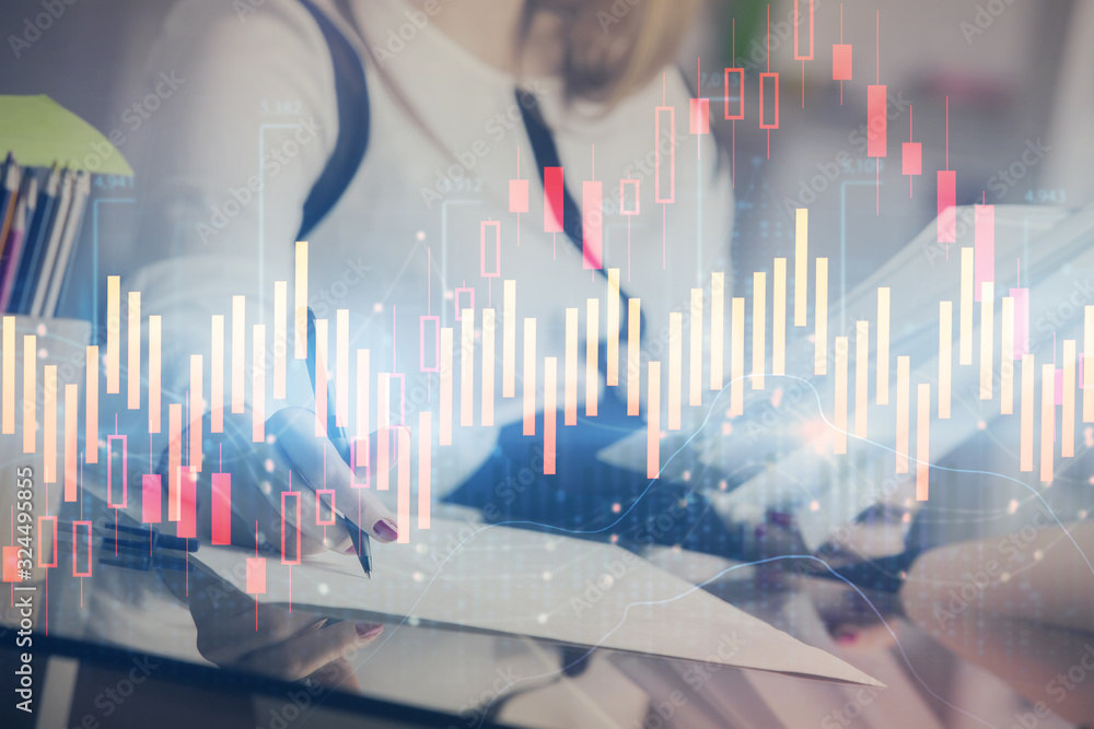 A woman hands writing information about stock market in notepad. Forex chart holograms in front. Concept of research. A woman hands writing information about stock market in notepad. Forex chart holograms in front. Concept of research.