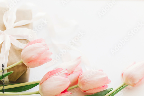 Fototapeta Naklejka Na Ścianę i Meble -  Pink tulips and gift box with ribbon on white background. Stylish tender image. Happy womens day. Greeting card with space for text. Happy Mothers day. Wedding or valentine celebration